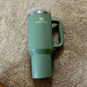 A blueish green 40oz Stanley tumbler with handle.